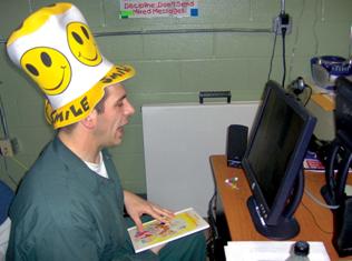 Picture of man with funny hat looking at computer screen.