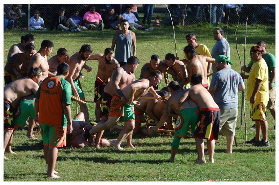 Photo of men playing lacrosse-like game.